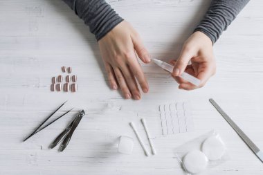 The process of putting artificial (fake) fingernail on the finger. Woman manicure. Flat lay.