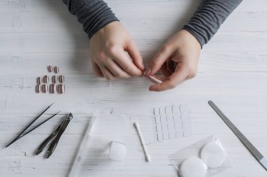 The process of putting artificial (fake) fingernail on the finger. Woman manicure. Flat lay.