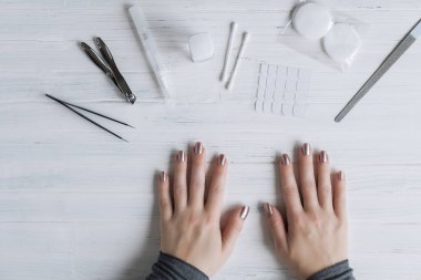 The process of putting artificial (fake) fingernail on the finger. Woman manicure. Flat lay.