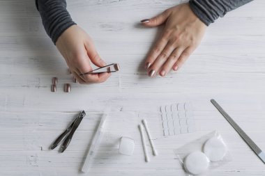The process of putting artificial (fake) fingernail on the finger. Woman manicure. Flat lay.