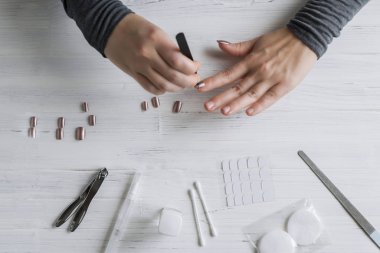 The process of putting artificial (fake) fingernail on the finger. Woman manicure. Flat lay.