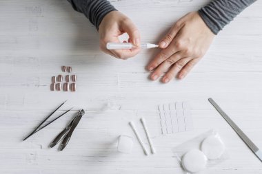 The process of putting artificial (fake) fingernail on the finger. Woman manicure. Flat lay.