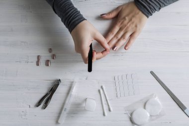The process of putting artificial (fake) fingernail on the finger. Woman manicure. Flat lay.