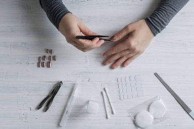 The process of putting artificial (fake) fingernail on the finger. Woman manicure. Flat lay.
