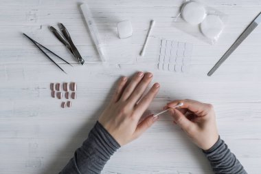 The process of putting artificial (fake) fingernail on the finger. Woman manicure. Flat lay.