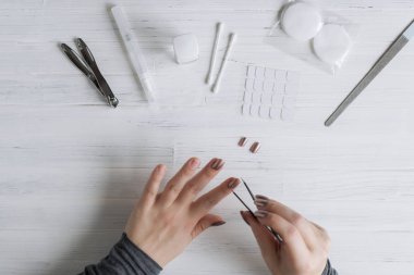 The process of putting artificial (fake) fingernail on the finger. Woman manicure. Flat lay.