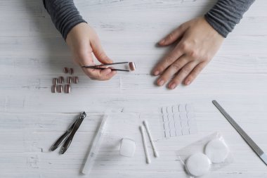 The process of putting artificial (fake) fingernail on the finger. Woman manicure. Flat lay.
