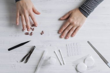 The process of putting artificial (fake) fingernail on the finger. Woman manicure. Flat lay.