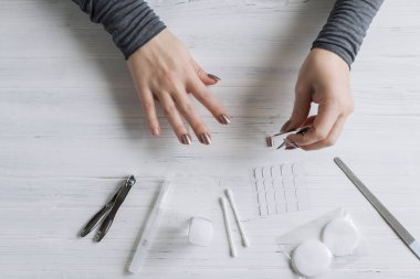 The process of putting artificial (fake) fingernail on the finger. Woman manicure. Flat lay.