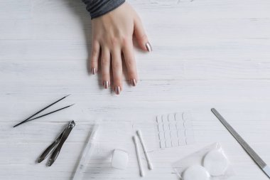 The process of putting artificial (fake) fingernail on the finger. Woman manicure. Flat lay.