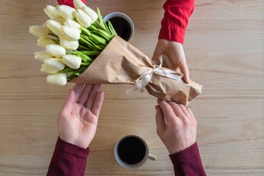 Valentines day.  Close-up of woman and man celebrating in restaurant. Boyfriend giving bouquet of tulips to girlfriend. love, romance, date. Flat lay