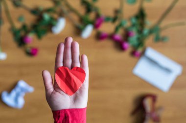 woman with crumpled paper heart in the hand sitting on the floor.  Broken relationships in bad Valentine's day. concept. Top view