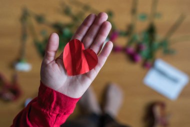 woman with crumpled paper heart in the hand sitting on the floor. breakup. bad Valentine's day. concept.