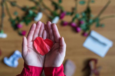 woman with crumpled paper heart in the hand sitting on the floor.  Broken relationships in bad Valentine's day. concept. Top view