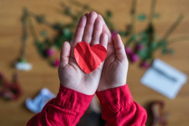 woman with crumpled paper heart in the hand sitting on the floor.  Broken relationships in bad Valentine's day. concept. Top view