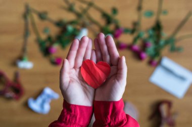 woman with crumpled paper heart in the hand sitting on the floor.  Broken relationships in bad Valentine's day. concept. Top view