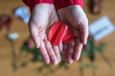 woman with crumpled paper heart in the hand sitting on the floor.  Broken relationships in bad Valentine's day. concept. Top view