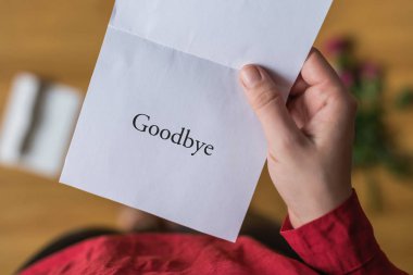 woman with paper letter and word goodbye on a floor. Heart broken concept. Copy Space