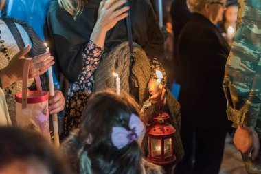 Kilise ayini sırasında elinde mum tutan insanlar.