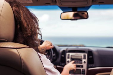 Otomobil gezisinde araba kullanan bir kadın arkada okyanus tropik plajı boyunca seyahat ediyor. Gezgin konsepti. Arka plan