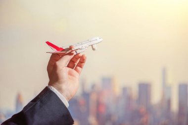 New York gökdelenlerinin arka planında oyuncak uçak tutan mavi takım elbiseli adamın eli. Kavram. 