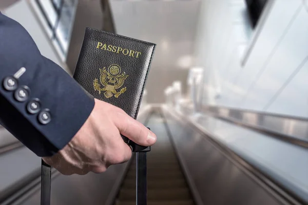身穿蓝色西装 手提箱中装有美国护照的人 在机场自动扶梯上 — 图库照片