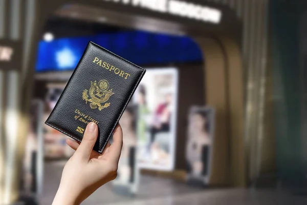 Woman hand holding american passport  in the airport duty free. concept.