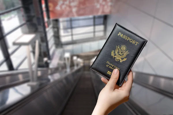 在机场自动扶梯上持有美国护照的妇女 — 图库照片