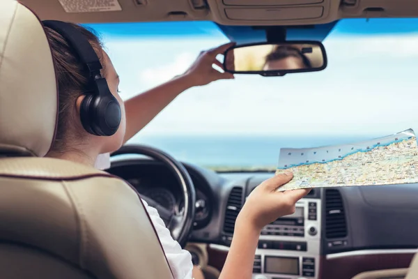 Γυναίκα Οδηγός Στα Ακουστικά Οδηγεί Ένα Αυτοκίνητο Και Κοιτάζοντας Χάρτη — Φωτογραφία Αρχείου
