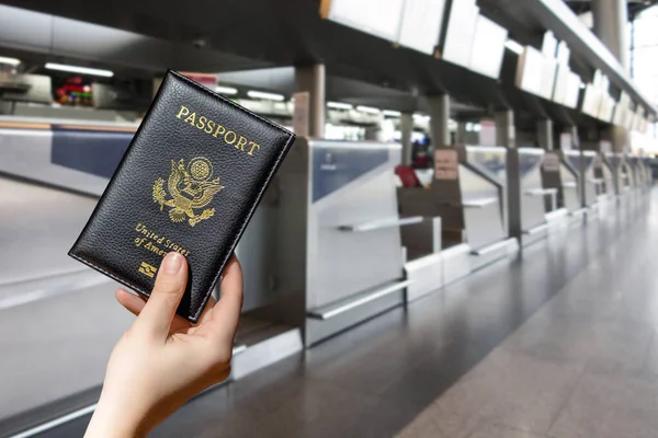 Woman hand holding american passport  in the airport opposite check-in area. concept. America. USA