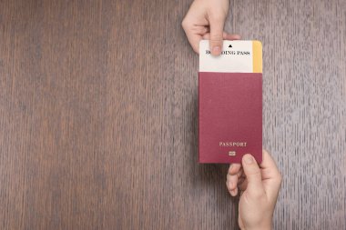 Pasaportu olan kadın elleri tahta masa, seyahat ve tatil konseptini aşıyor.