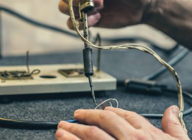 İnsan ellerine, lehim demirine, aletine ve kablolarına yakın çekim. Evde lehimleme işlemi