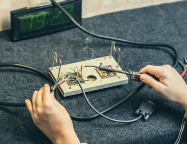 İnsan ellerine, lehim demirine, aletine ve kablolarına yakın çekim. Evde lehimleme işlemi