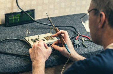 Erkek ellerine, lehim demirine, aletine ve kablolarına yakın çekim yapın. Evde lehimleme işlemi