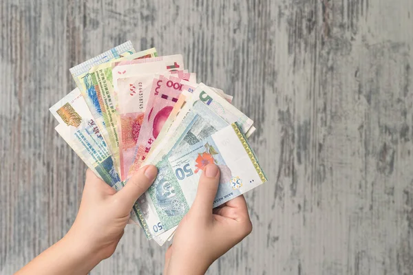 Kadın elleri tahtadan arka planda para banknotlarını tutuyor.