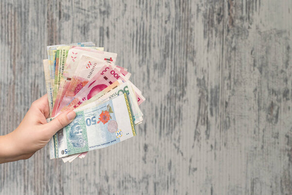 female hands holding money bills over wooden background