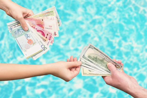 female hands exchanging money bills over blue background