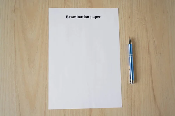 Empty examination paper for university with pen on the school desk. Copyspace. Mockup. Flat lay
