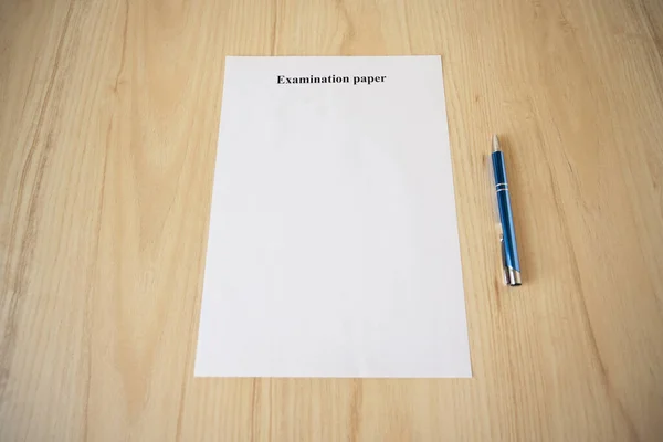 Empty examination paper for university with pen on the school desk. Copyspace. Mockup. Flat lay