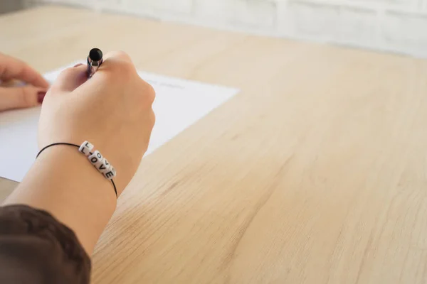 Student Meisje Hand Met Armband Liefdeswoord Leeg Onderzoeksformulier Tafel Eerste — Stockfoto