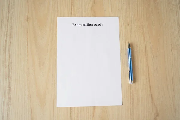 Empty examination paper for university with pen on the school desk. Copyspace. Mockup. Flat lay