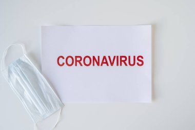 Ofis masasında duran bir kağıt parçasında Coronavirus kelimesi. Dünya çapında salgın konsepti, üretim ve iş durdurma