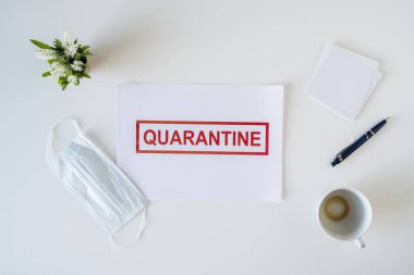 Coronavirus ve karantina yüzünden ofiste hasta bir çalışanın terkedilmiş işyeri. Tıbbi maske, peçete ve bir fincan bitmiş kahve ile birlikte. Dünya çapında salgın konsepti