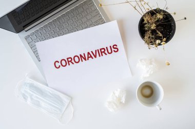 Coronavirus ve karantina yüzünden ofiste hasta bir çalışanın terkedilmiş işyeri. Tıbbi maske, peçete ve bir fincan bitmiş kahve ile birlikte. Dünya çapında salgın konsepti