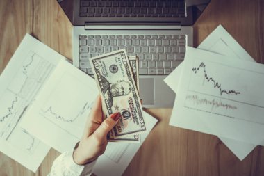 Kadın banknot paketini elinde tutan serbest çalışan elli Amerikan doları ve kârı ve geliri de sayıyor. Ofis masasındaki kağıda grafikler ve çizelgeler basılmış. Eski bir takas. Düz yatıyordu