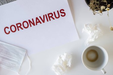 Coronavirus ve karantina yüzünden ofiste hasta bir çalışanın terkedilmiş işyeri. Tıbbi maske, peçete ve bir fincan bitmiş kahve ile birlikte. Dünya çapında salgın konsepti