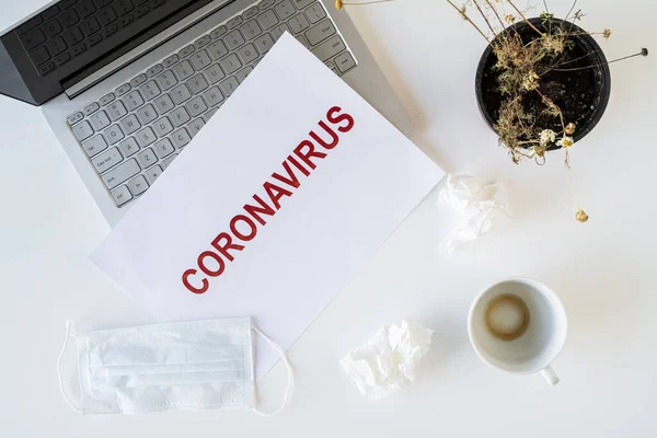 Coronavirus ve karantina yüzünden ofiste hasta bir çalışanın terkedilmiş işyeri. Tıbbi maske, peçete ve bir fincan bitmiş kahve ile birlikte. Dünya çapında salgın konsepti