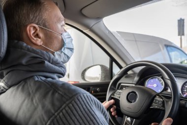 Kendini araba kullanan bakteri ve virüsten korumak için maske takan orta yaşlı bir adamın yüzü. Coronavirus. Salgın