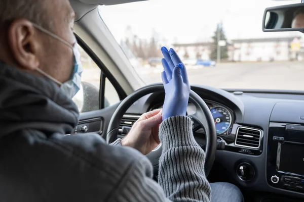 医療マスクの男は 車を運転しながら細菌やウイルスから身を守るためにゴム手袋を着用しています コロナウイルス パンデミック — ストック写真