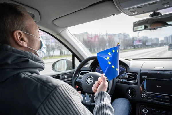 Middle aged man in the medical mask with Germany flag driving a car. symbol of adverse epidemiological situation in countries. Coronavirus. Pandemic